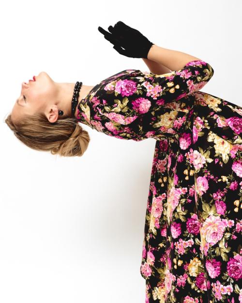 Дівчина в образі 50-х років позирує в розкльошеній квітковій сукні з під'юбником