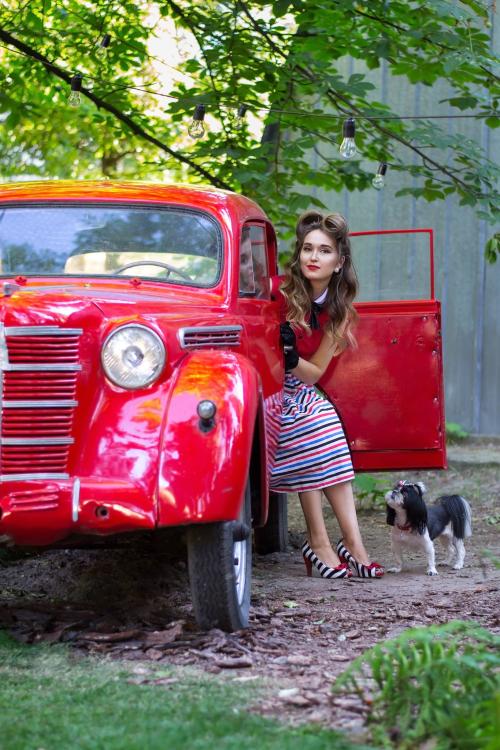 Дівчина у ретро сукні виходить з червоного ретро авто