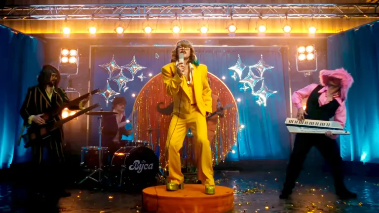 Артем Пивоваров у яскраво-жовтому костюмі-трійці та взутті на платформі виступає на сцені в ретро-стилі 70-х.